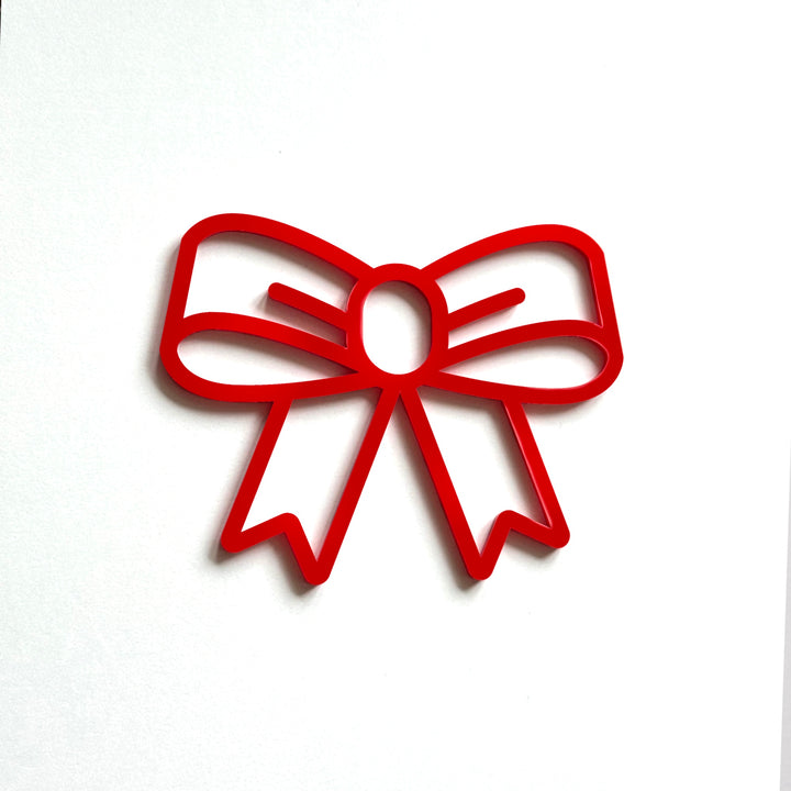 A red bow-shaped cutout is displayed against a white background. A red bow-shaped cutout is displayed against a white background.