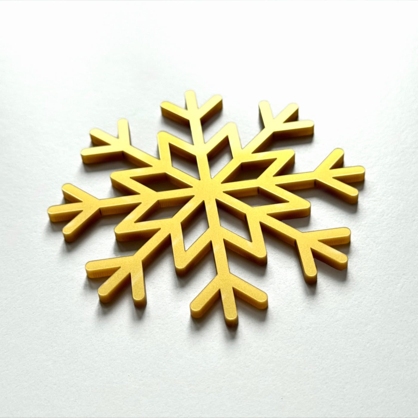 A golden snowflake-shaped object is displayed against a white background.