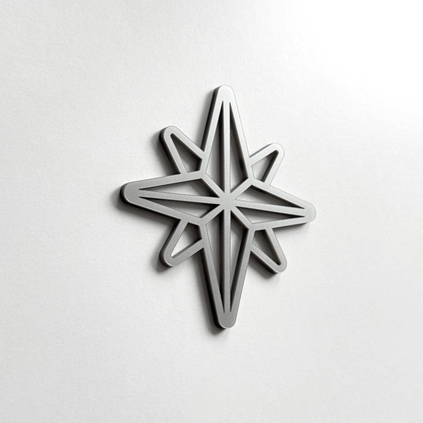 A silver star-shaped object is mounted on a white wall.