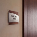 a sign with the text "YOUR TEXT HERE" and some Braille text below it, mounted on a wall next to a wooden door. - Photo #2
