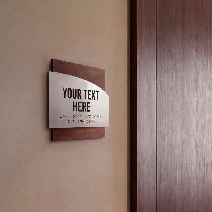 a sign with the text "YOUR TEXT HERE" and some Braille text below it, mounted on a wall next to a wooden door.