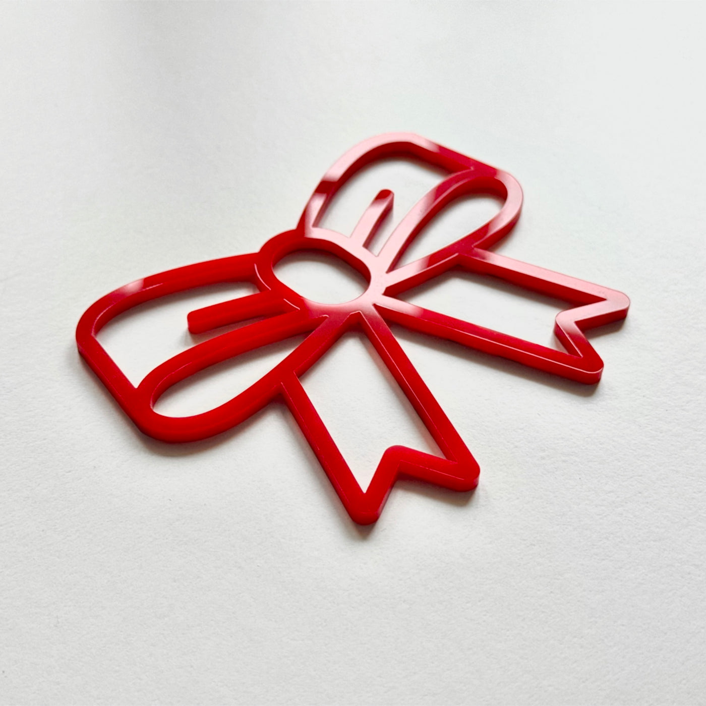 A red plastic bow-shaped object is shown against a white background.