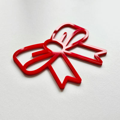 A red plastic bow-shaped object is shown against a white background.