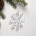 A white snowflake ornament is hanging from a branch of a pine tree. - Photo #2