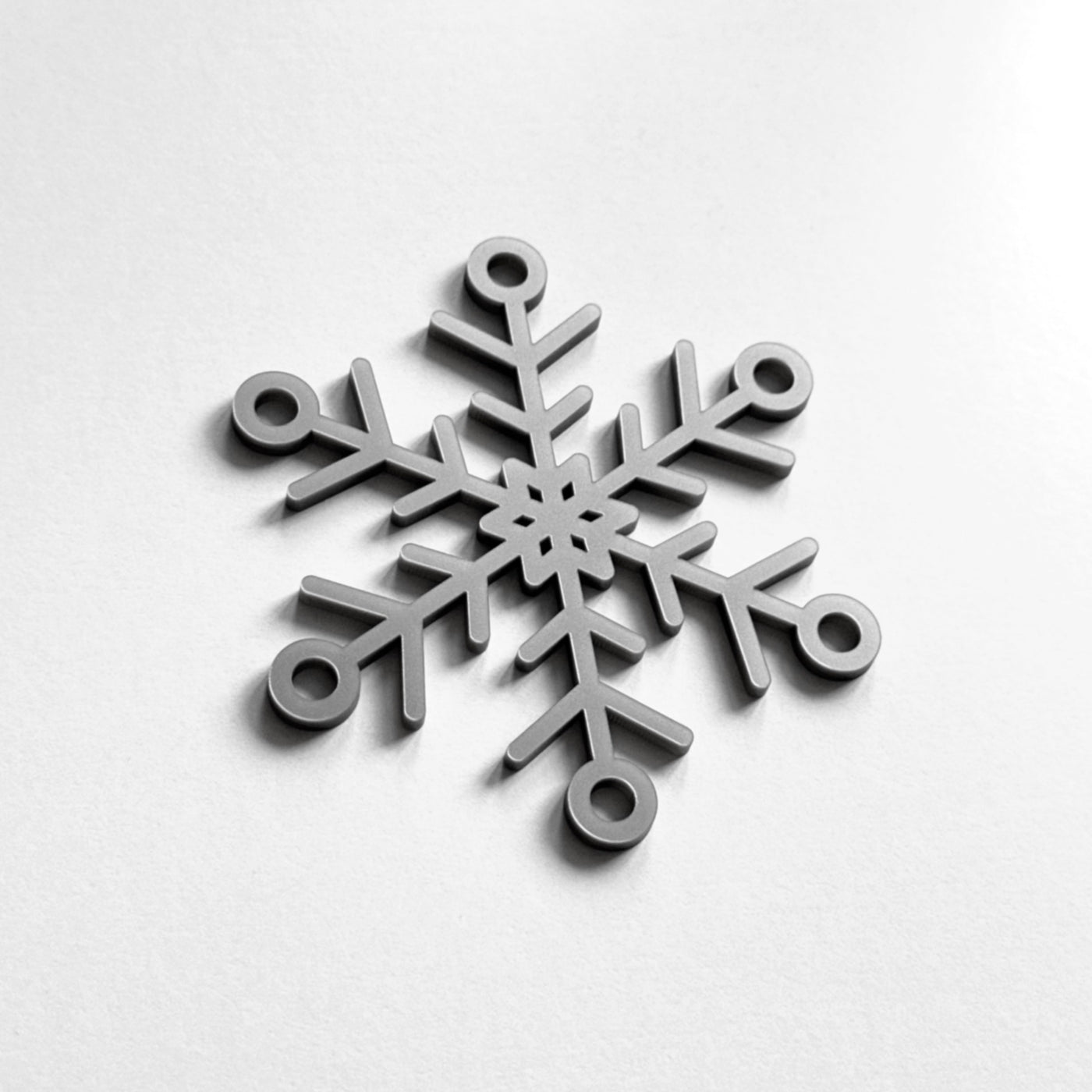 A silver snowflake ornament is displayed against a white background.
