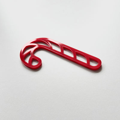 A red plastic candy cane decoration is shown against a plain white background.
