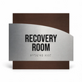 a sign that reads "RECOVERY ROOM" in bold black letters, with a small "B" symbol below the text, indicating the use of Braille or a similar tactile format for accessibility. - Photo #1