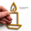 A hand is holding a yellow candle-shaped ornament with a text overlay instructing to remove the protective film from both sides of the ornament for a clean, glossy look. - Photo #8