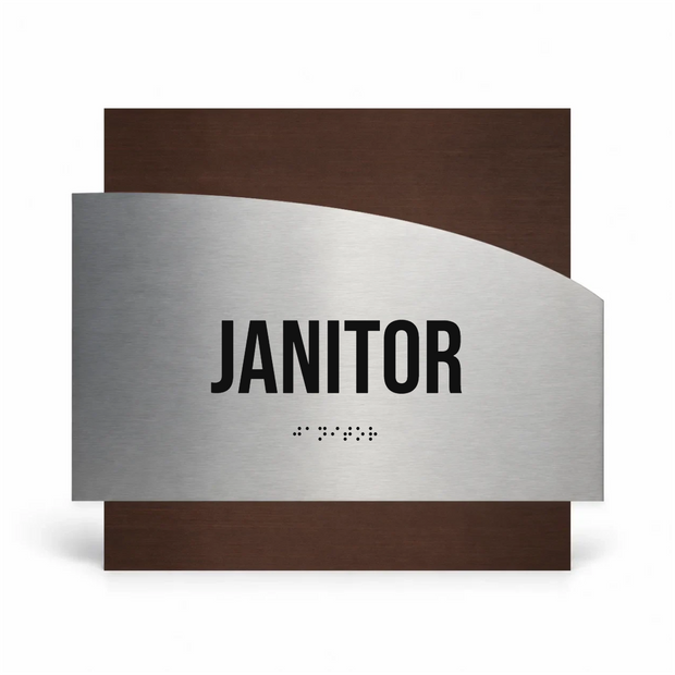 a sign that reads "JANITOR" in bold black letters, with a small "B" symbol below the text, indicating the use of Braille or a similar tactile format for the sign.