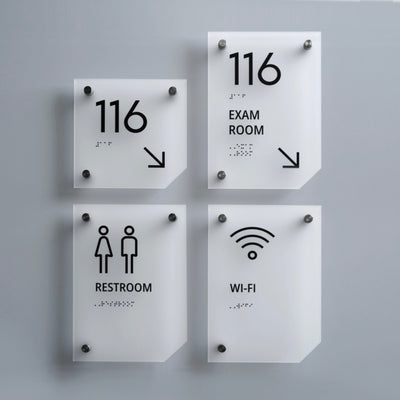 a set of four restroom signs mounted to the side of a wall