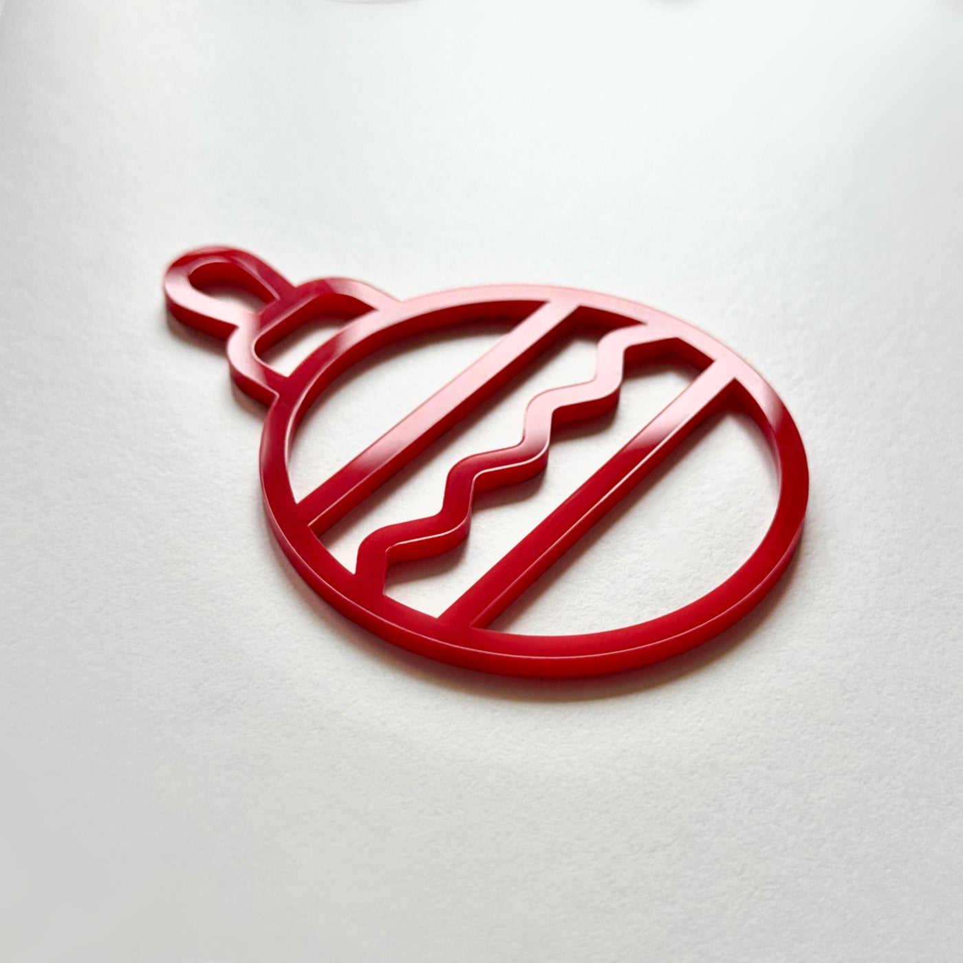 A red ornament with a wavy pattern is shown against a white background.