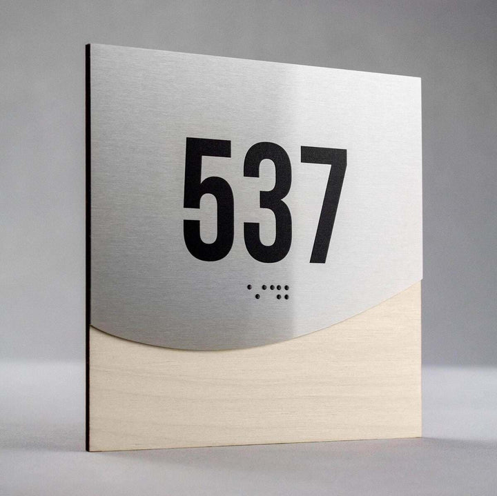 Jure design room number sign 537 with raised numerals and Braille, brushed metal and light wood interior signage